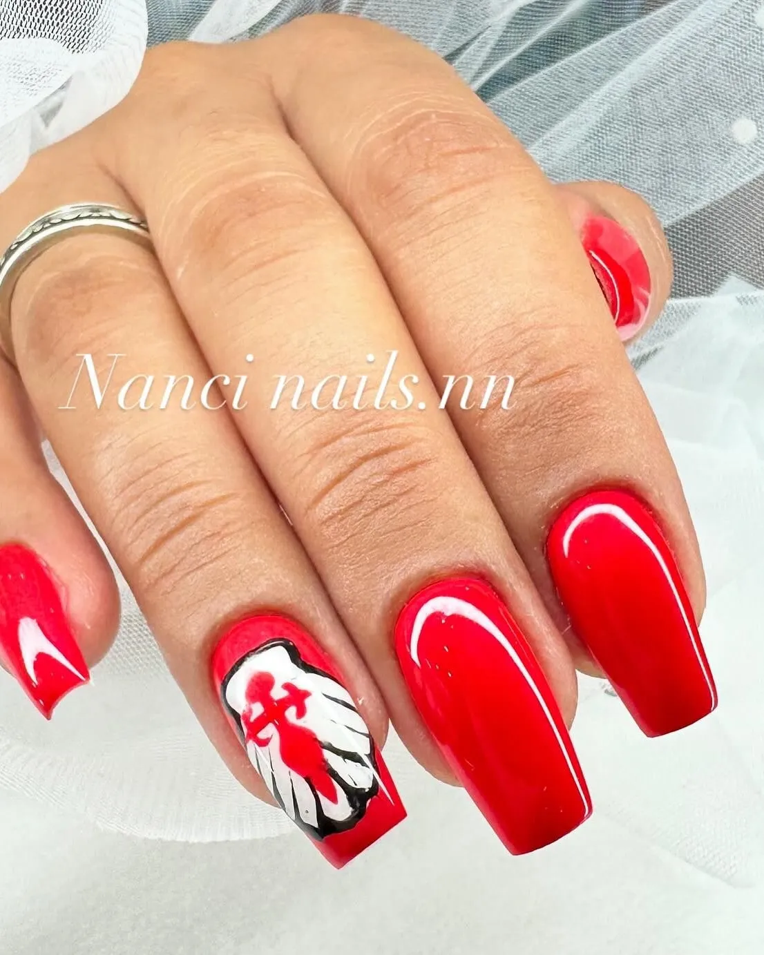 Uñas rojas con un diseño en blanco y negro pintado a mano